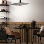 Minimalist_composition_of_living_room_interior_with_black_round_coffee_table,_stylish_chair,_wooden_sideboard,_dark_wall_with_stucco,_pitcher,_lamp_and_personal_accessories._Home_decor._Template.