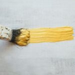 Brush_with_gold_paint_on_white_wooden_baclground